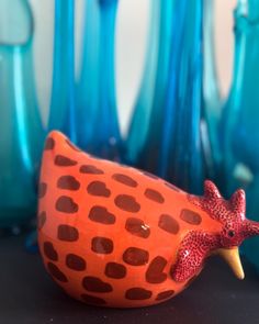 a ceramic bird sitting on top of a table next to blue vases