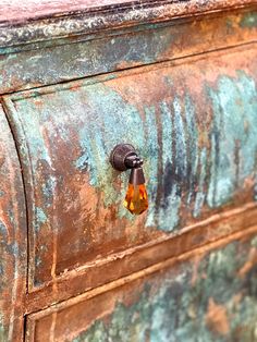 a rusted metal drawer with an orange glass knob on the top and bottom part