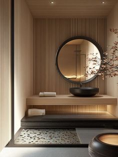 a round mirror sitting on top of a wooden shelf next to a vase filled with flowers