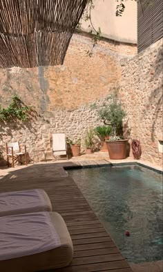 an outdoor swimming pool with chaise lounges and potted plants next to it