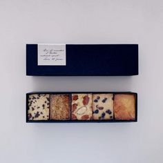 four different types of cookies in a black box with a white label on the top