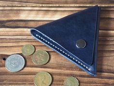 a black leather wallet and some coins on a wooden table