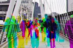 people walking across a bridge in the city with colorful colors on their body and legs