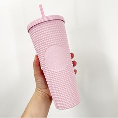 a hand holding a pink starbucks cup with a straw in it's sleeve and lid