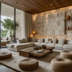 a living room filled with lots of furniture and walls covered in stone bricks, along with floor to ceiling windows