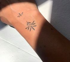 a person's arm with a small tattoo design on the left side of it