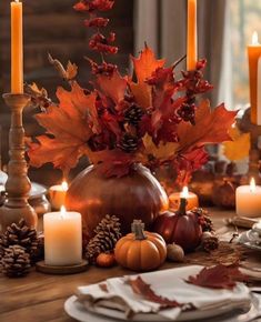 a table topped with candles and fall leaves on top of it's wooden table