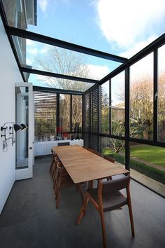 a dining room table and chairs in front of a large glass wall with sliding doors