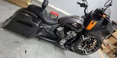 a black motorcycle parked in a garage next to some boxes and other items on the floor