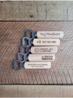 four bottle openers are sitting on top of a wooden table