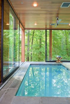 an indoor swimming pool in the middle of a house with glass walls and sliding doors