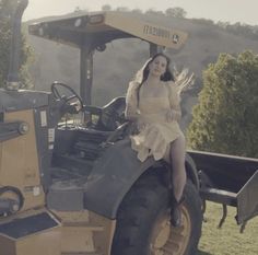 a woman sitting on the back of a tractor