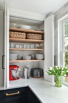 a kitchen with white counter tops and open shelves filled with plates, bowls and cups