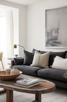 a living room filled with black couches and pillows on top of a wooden table