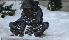 a statue of a person sitting in the snow