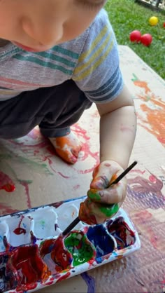 a young boy is painting with his hands