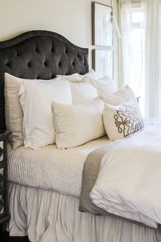 a bed with white sheets and pillows in a bedroom