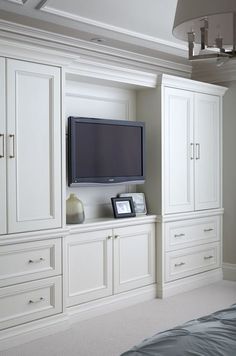 a flat screen tv mounted to the side of a white cabinet in a room with carpeted flooring