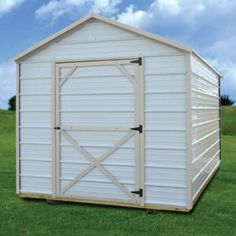 a white shed sitting on top of a lush green field