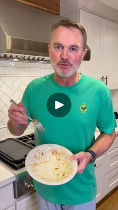 a man in a green shirt holding a plate with food on it