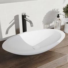 a white sink sitting on top of a wooden counter next to a faucet