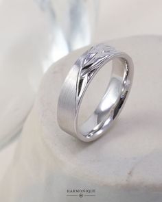 a white gold wedding ring on top of a rock