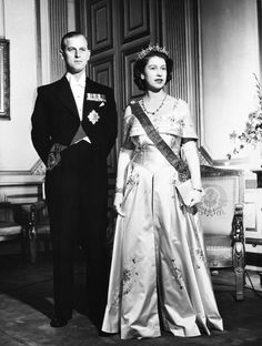 an old black and white photo of a man and woman in formal wear standing next to each other