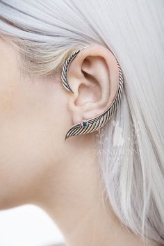 a woman with white hair wearing a pair of ear piercings in the shape of an arrow