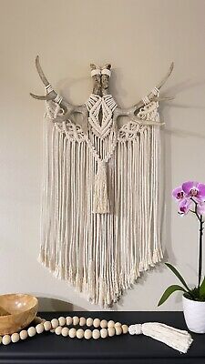 a table topped with a vase filled with flowers and beads next to a wall hanging