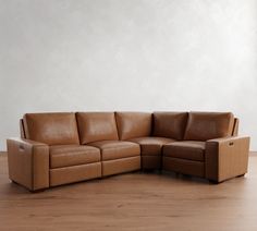 a brown leather couch sitting on top of a wooden floor next to a white wall