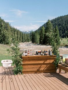 an outdoor bar on a deck with chairs and tables in the foreground, surrounded by trees