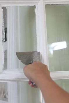 a person is holding a knife in front of a window that has been torn off