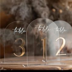 three clear acrylic table numbers with gold numbers on each one and the number thirteen