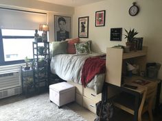 a bed room with a neatly made bed next to a window and a small desk