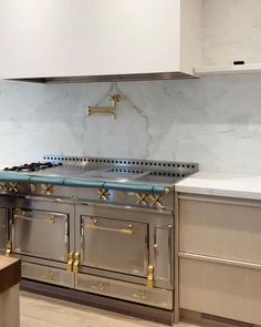 a stove top oven sitting inside of a kitchen next to a wall mounted range hood