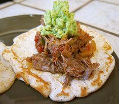 a tortilla topped with meat and guacamole