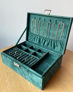 an open green velvet jewelry box on a wooden table with several pairs of earrings in it