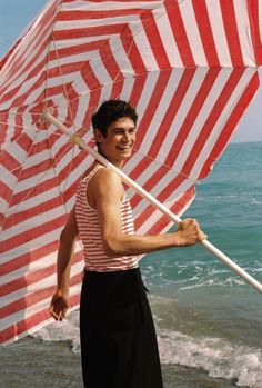 a man holding an umbrella on the beach