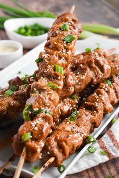 chicken skewers with sauce and green onions on a plate