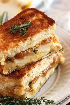 two grilled cheese sandwiches stacked on top of each other with fresh thyling sprigs