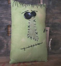 a green pillow with black buttons on the front and back of it, sitting on a wooden surface