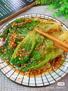 a plate topped with green vegetables and chopsticks next to a menu on a table