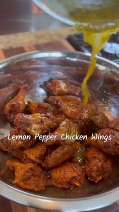 a bowl full of chicken wings being drizzled with lemon pepper and mustard