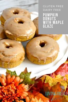 pumpkin donuts with maple glaze on a white plate surrounded by fall leaves and flowers