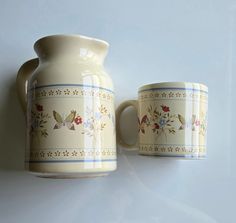 two coffee mugs sitting next to each other on a white tableclothed surface