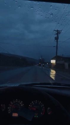 the dashboard of a car with rain drops on it and power lines in the background