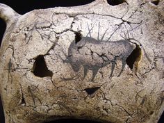 an animal carved into the side of a rock with holes in it's surface