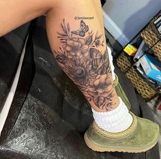 a woman's leg with flowers and butterflies tattoo on her left arm, sitting on a chair