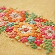 an embroidered piece of cloth with colorful flowers on the bottom and green, red, yellow, orange, and pink colors