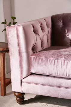 a pink velvet chair sitting on top of a wooden table